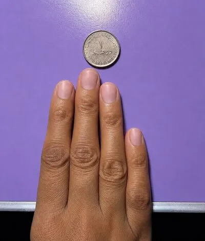 Full hand with coin for nail sizing