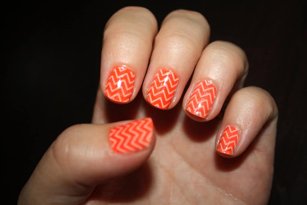 female hand with orange chevron nails