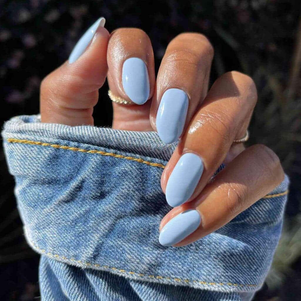A girl showing off blue nail color with a denim sleeve x
