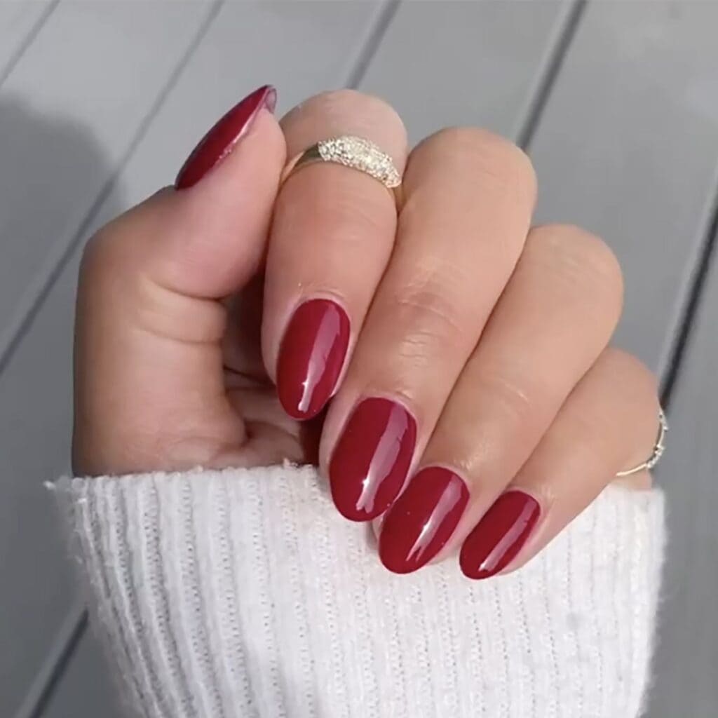 A hand displaying bright red cranberry nails for thanksgiving x
