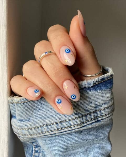 A hand showing off blue evil eye design on nails