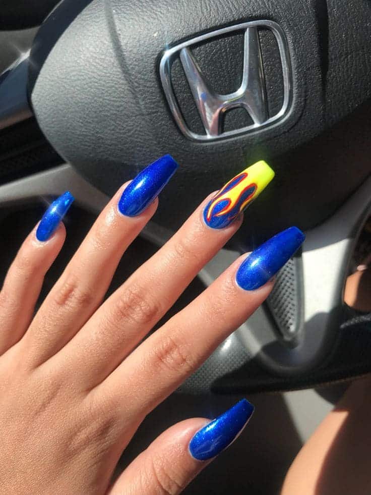 A hand showing off dark blue and yellow fire nail art