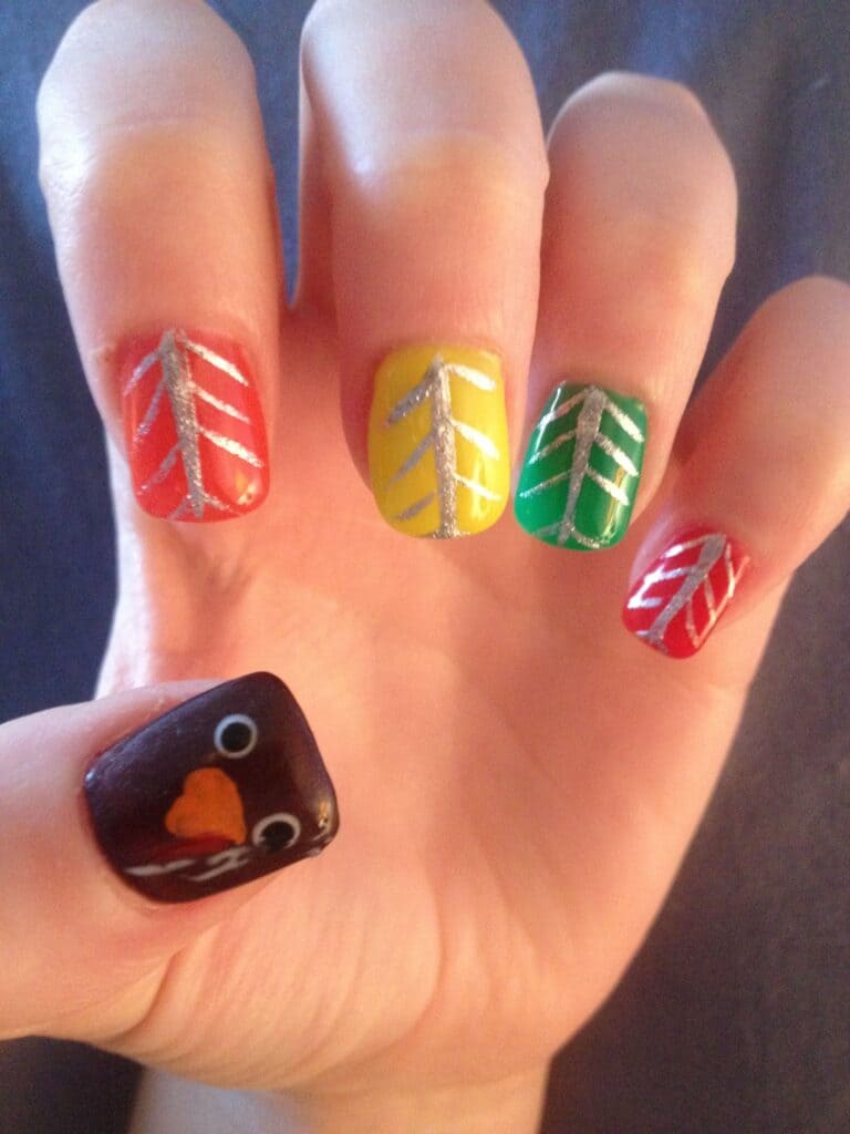 A nail showing multicolor turkey feathers on four fingers and turkey face on one x