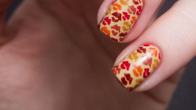 A view of a hand showing red and orange Autumn Kisses Thanksgiving Nail Design