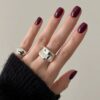 A view of hand with rings and burgundy colored nail paint