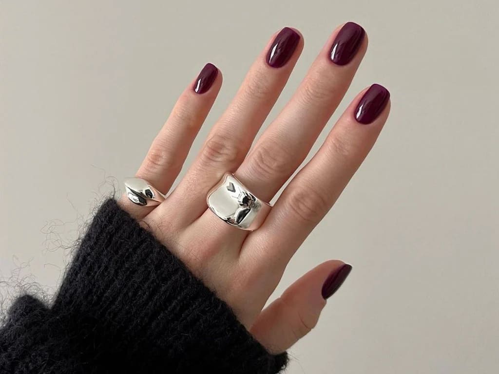 A view of hand with rings and burgundy colored nail paint
