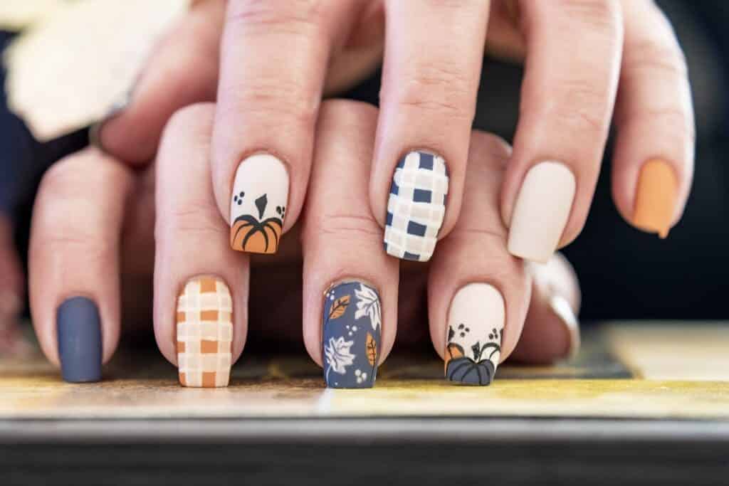A view of hands on one another with Pumpkin and Plaid Accent Nails x