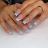 A view of hands with baby blue french tips on square nails x