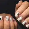 Milky white nails with black leafy patterns