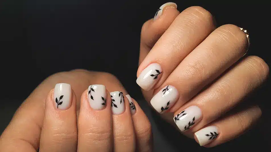 Milky white nails with black leafy patterns