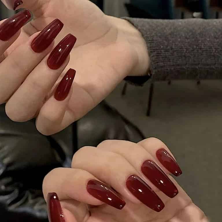 Two hands displaying Jelly tinted press on burgundy nails