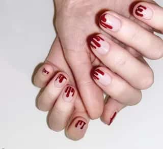 Two hands displaying a halloween burgundy dripping nail art