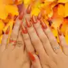 A view of burnt orange nails over autumn leaves