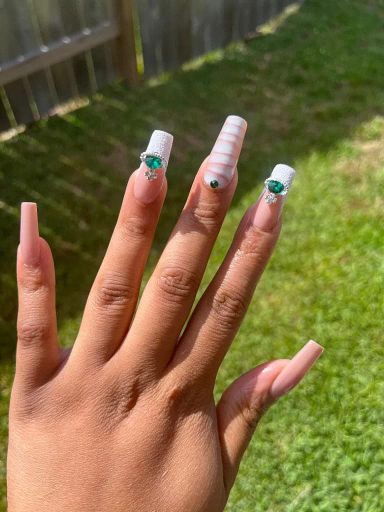 A hand displaying long tapered nails with gemstones on them x A hand displaying long tapered nails with gemstones on them x