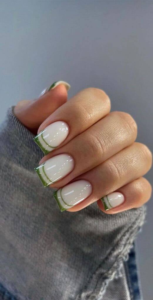 A hand showing classic glossy tow toned square nails with white and green shades x A hand showing classic glossy tow toned square nails with white and green shades x
