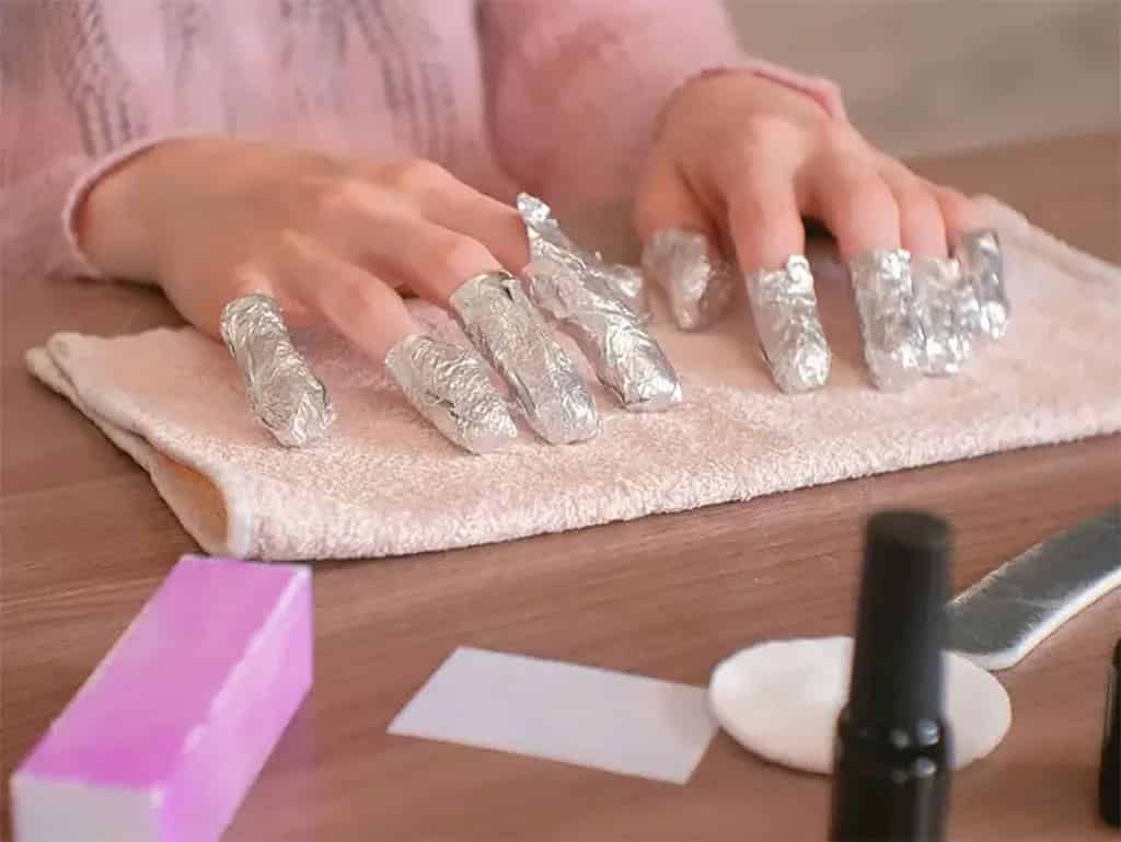 A view of hands in foil for polygel removal step A view of hands in foil for polygel removal step