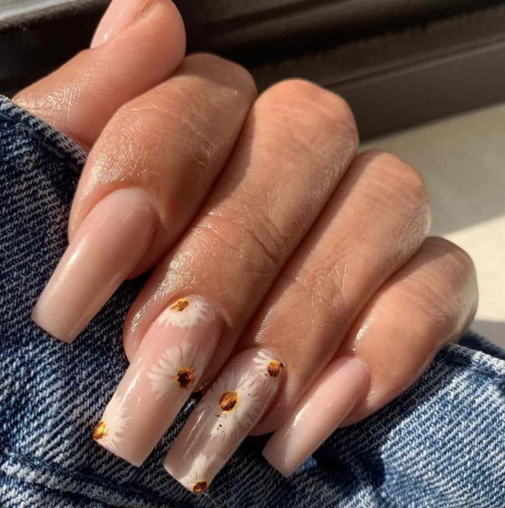 A view of hands with long square nails with nude paint and flower design on them x A view of hands with long square nails with nude paint and flower design on them x