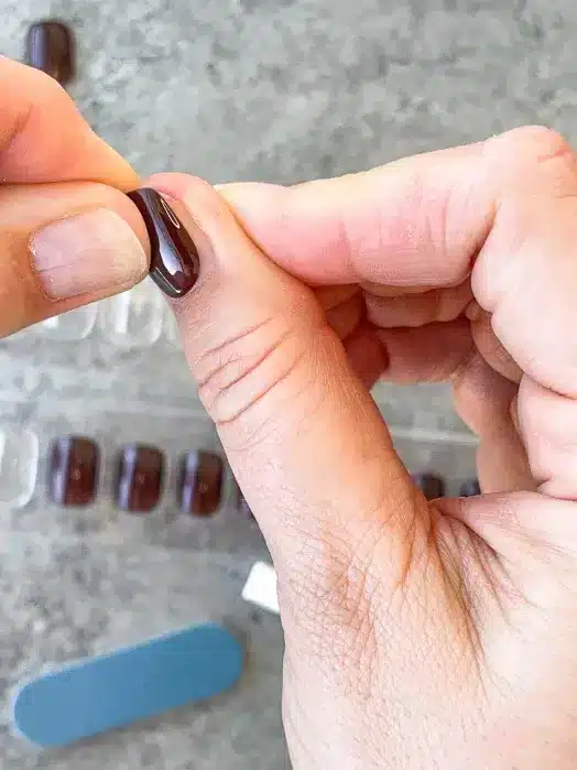 A view of a person applying maroon press on nails A view of a person applying maroon press on nails