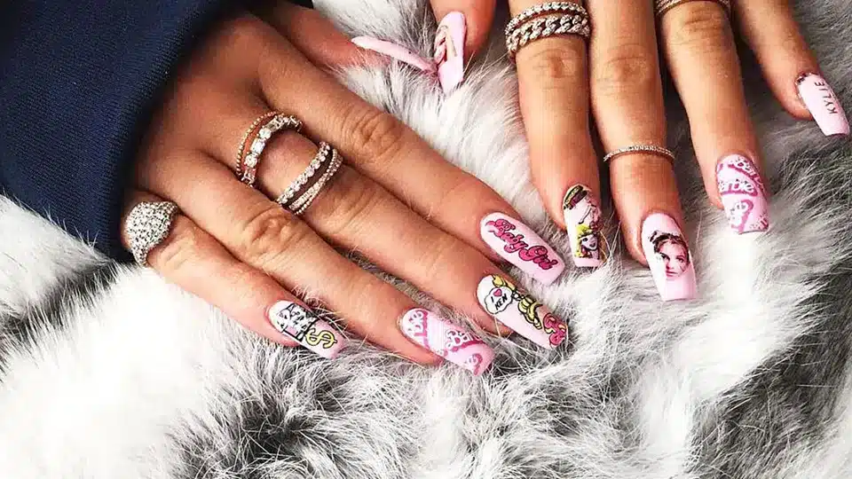 An overhead view of a girls hands wearing rings and pink press on nail with design An overhead view of a girls hands wearing rings and pink press on nail with design