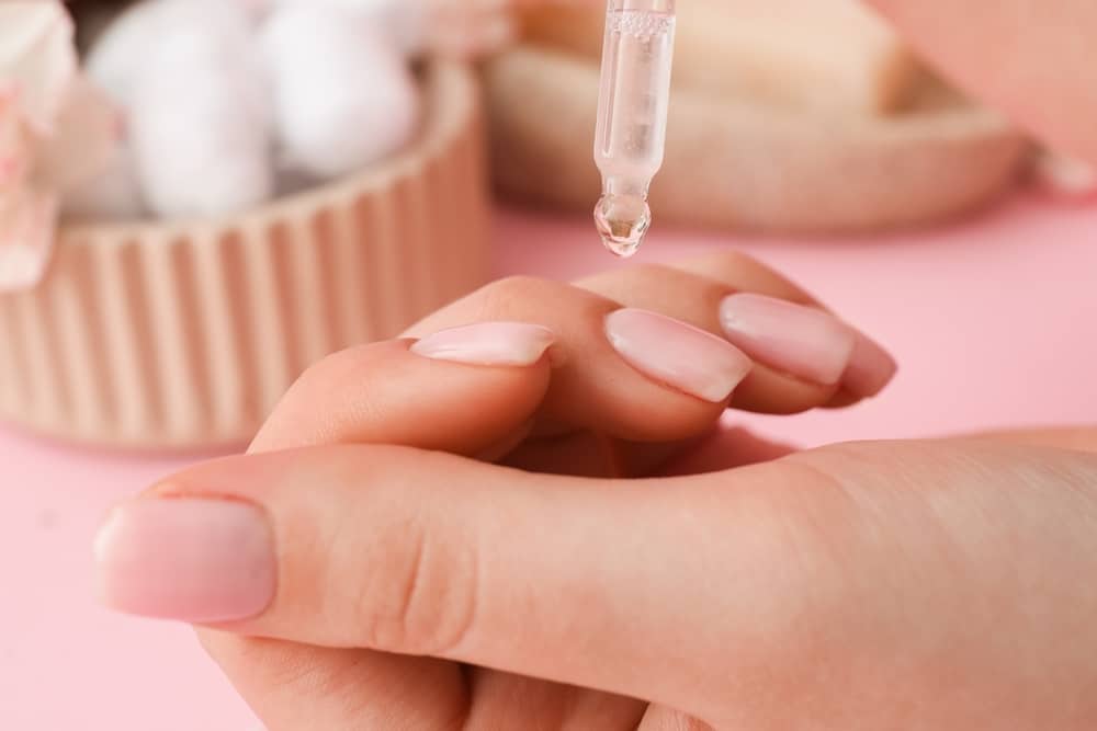 A view of a girl applying cuticle oil on her nails A view of a girl applying cuticle oil on her nails