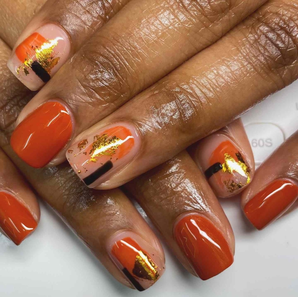 A view of orange nails with gold foil design A view of orange nails with gold foil design