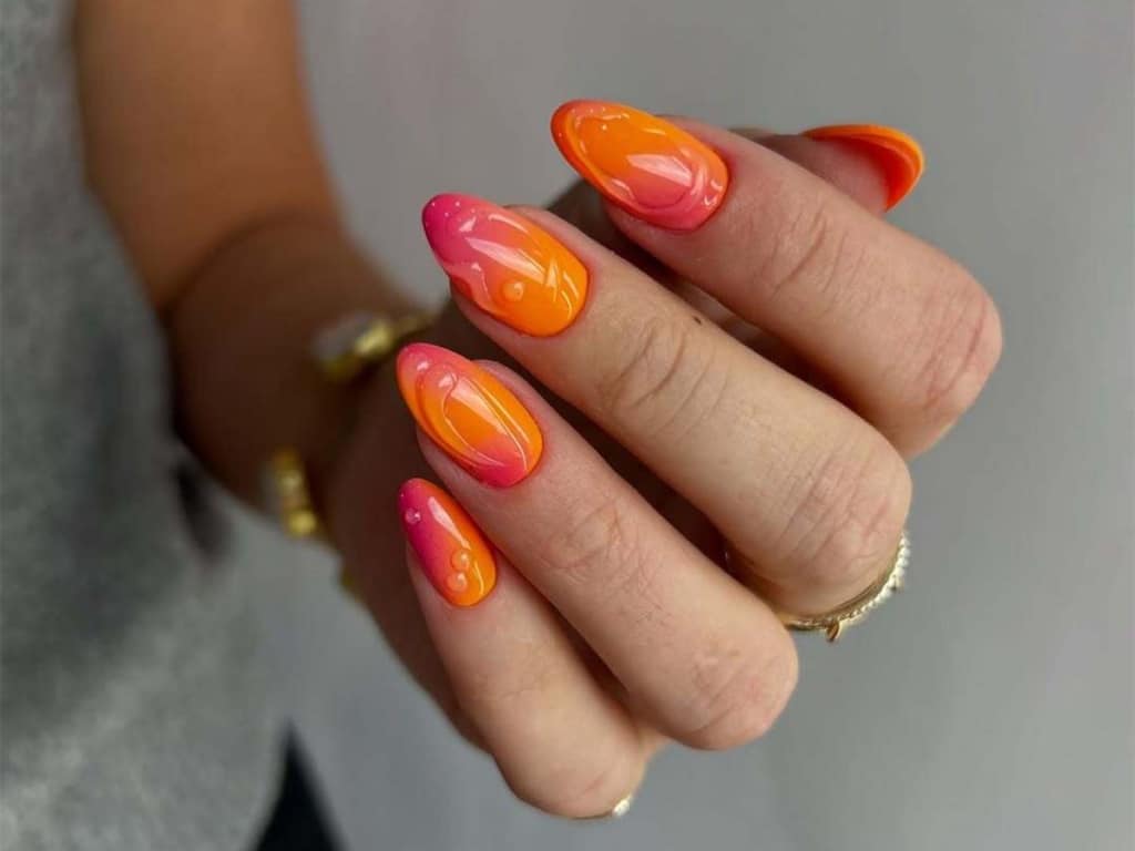 A view of pink and orange neon nail color on hands A view of pink and orange neon nail color on hands